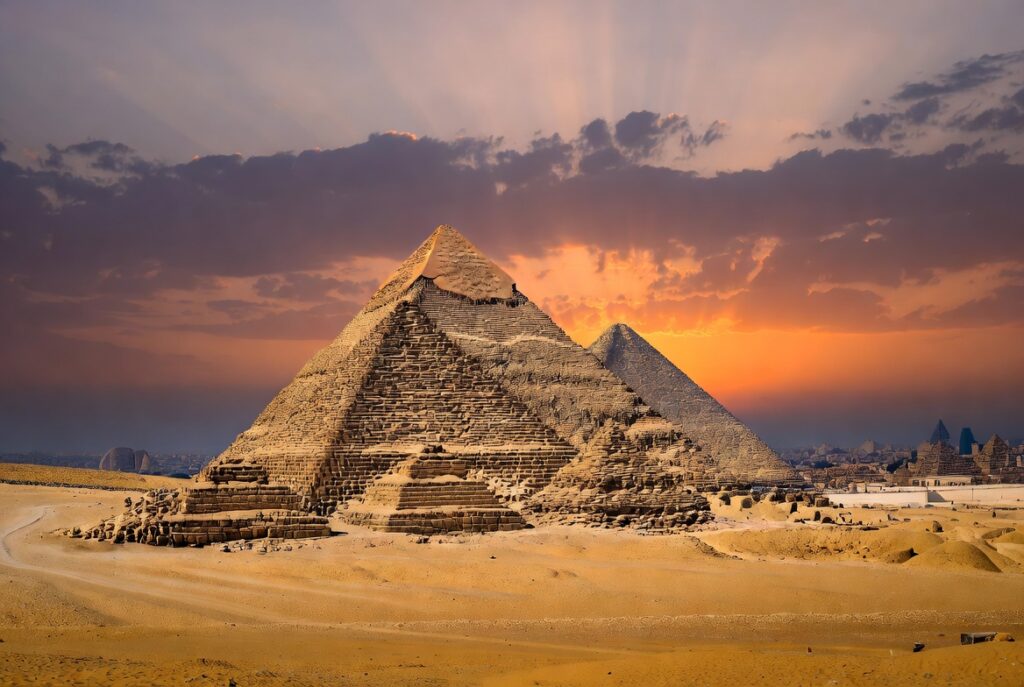 Egyptian Pyramids at Giza rising from the desert sands at sunset, showcasing the Great Pyramid of Khufu and ancient engineering marvels